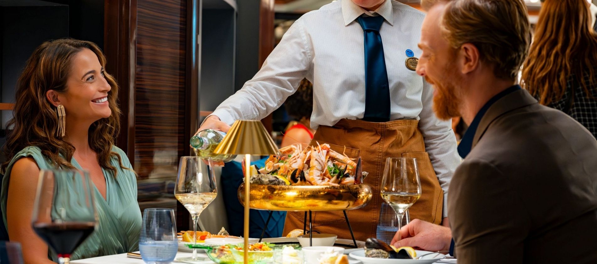 two people enjoying a meal in a restaurant on board the Enchanted Princess with their Princess Cruises package