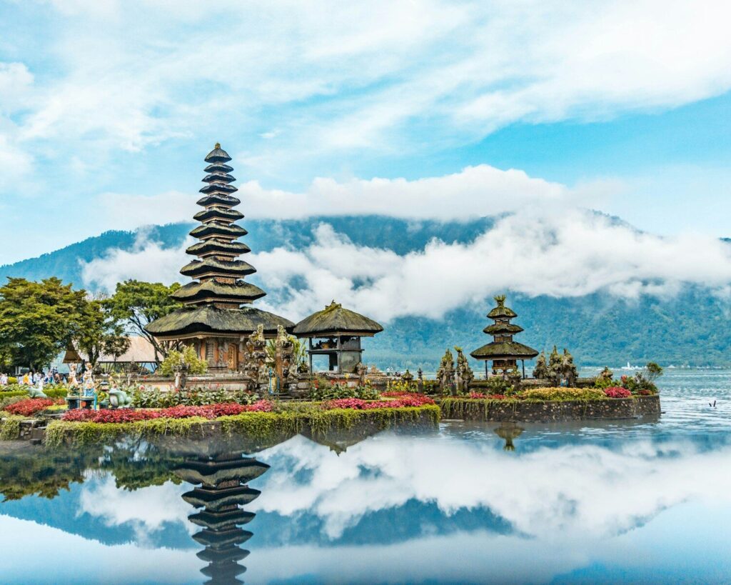brown and green temple near body of water under blue and white cloudy sky during daytime Bali, Indonesia